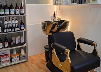 Silla dorada y estantería de productos en GABO LLOJA HAIR SALÓN AND BEAUTY, Barcelona, Catalunya, ES.