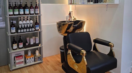 Silla dorada y estantería de productos en GABO LLOJA HAIR SALÓN AND BEAUTY, Barcelona, Catalunya, ES.