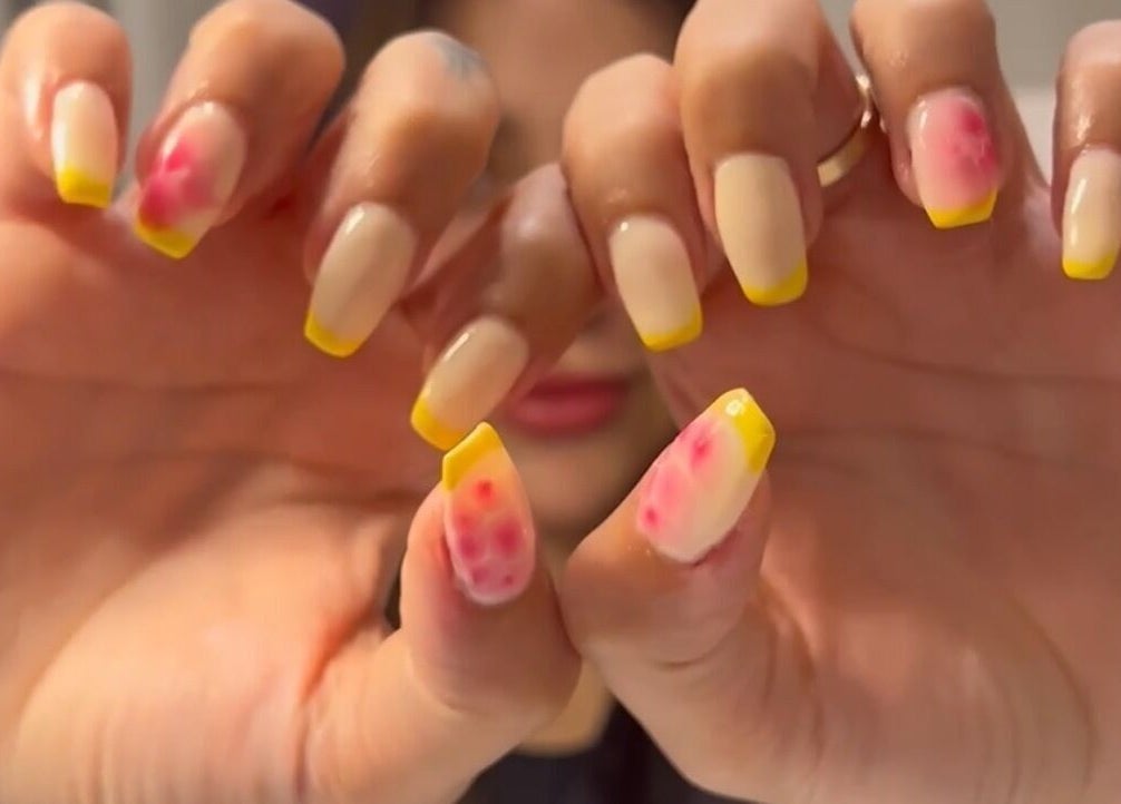 Colorful nail art at Glamorous Salon جلامورس صالون in Riyadh, SA featuring yellow tips and floral designs.