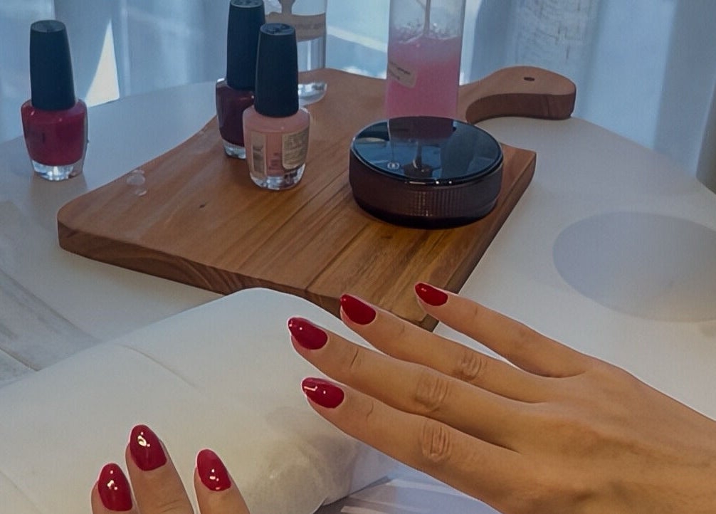 Manicure with red polish at Glamorous Salon جلامورس صالون, Riyadh, SA. Nail care products displayed.