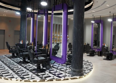Modern interior of Al Alami Barbershop العالمي in Jeddah, Makkah Province, SA featuring elegant purple mirrors.
