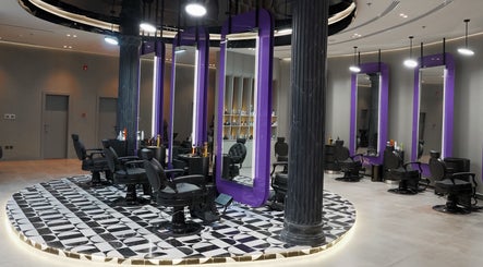 Modern interior of Al Alami Barbershop العالمي in Jeddah, Makkah Province, SA featuring elegant purple mirrors.