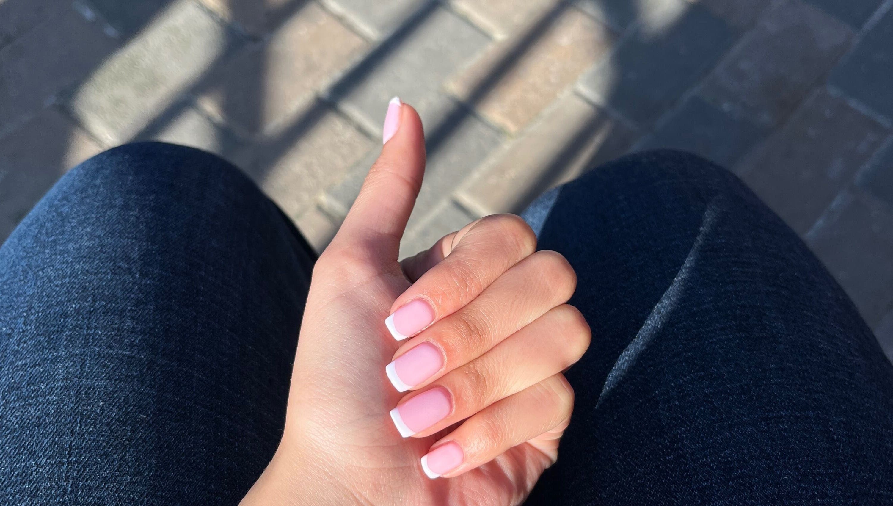 A hand with elegant French tip nails at Nailed by Nay, Cape Town, Western Cape, ZA.