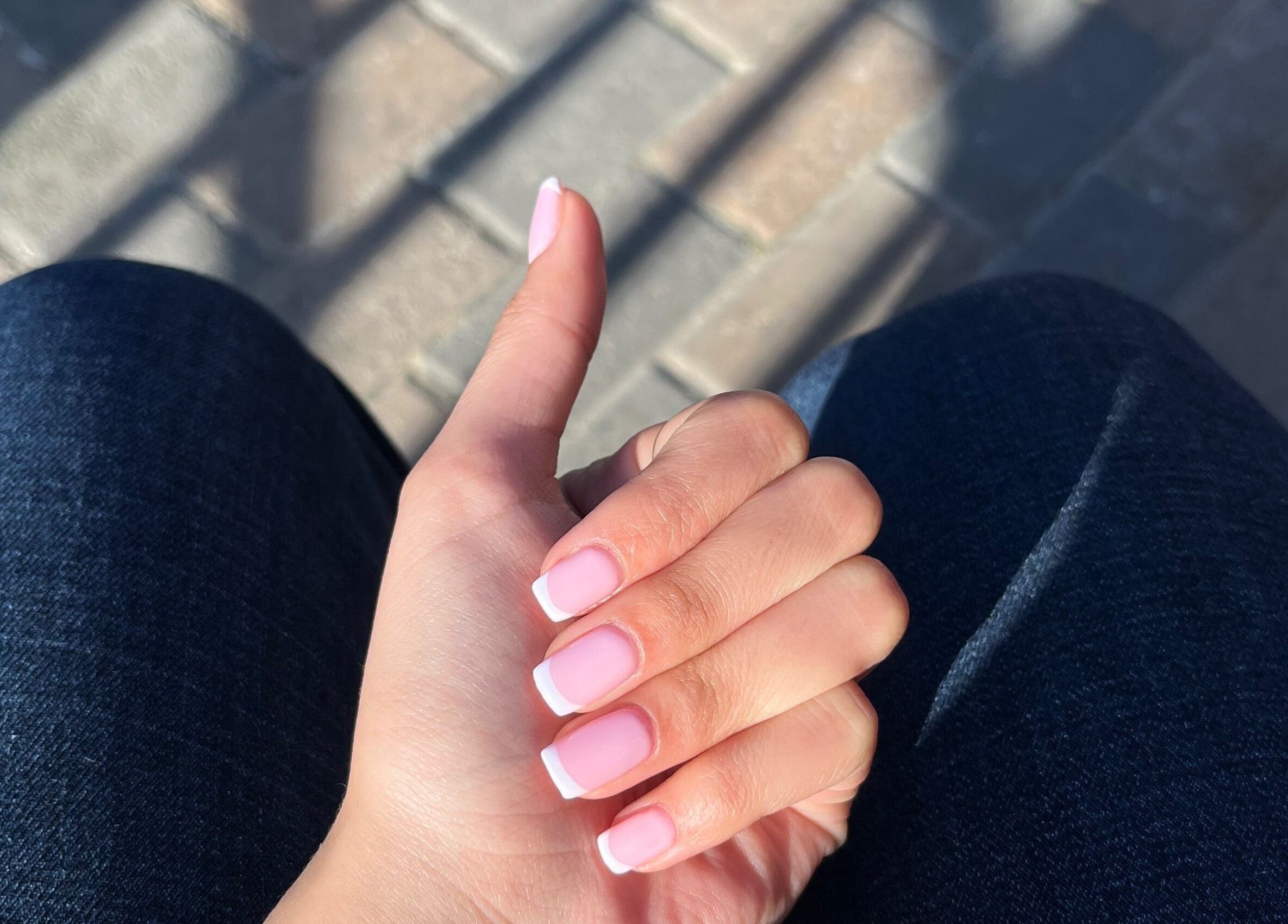 A hand with elegant French tip nails at Nailed by Nay, Cape Town, Western Cape, ZA.