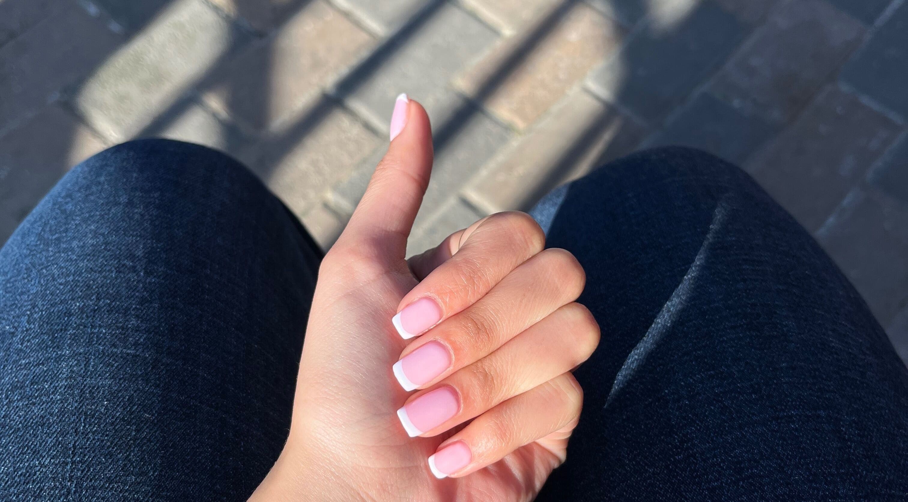 A hand with elegant French tip nails at Nailed by Nay, Cape Town, Western Cape, ZA.