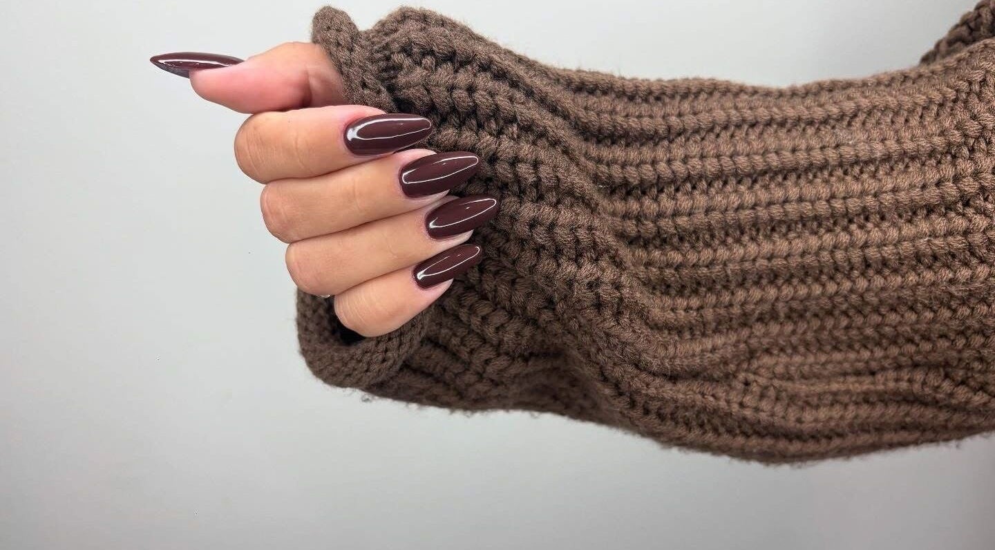 Elegant brown manicure on a hand wearing a knit sleeve at Just Beauty, Carlisle, England, GB.