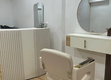 Estación de belleza minimalista en Moon Beauty, Valencia, Carabobo, VE, con espejo redondo y silla elegante.