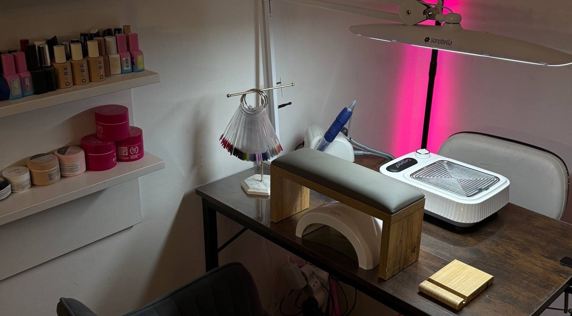 Stół do manicure salonu Sonni nails, Warszawa, Województwo Mazowieckie, PL z lampą, polerkami i paletą lakierów.