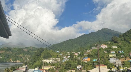 Scenic view from _Braided.by_bri, Kingstown, St. David, VC with lush green hills and colorful homes.