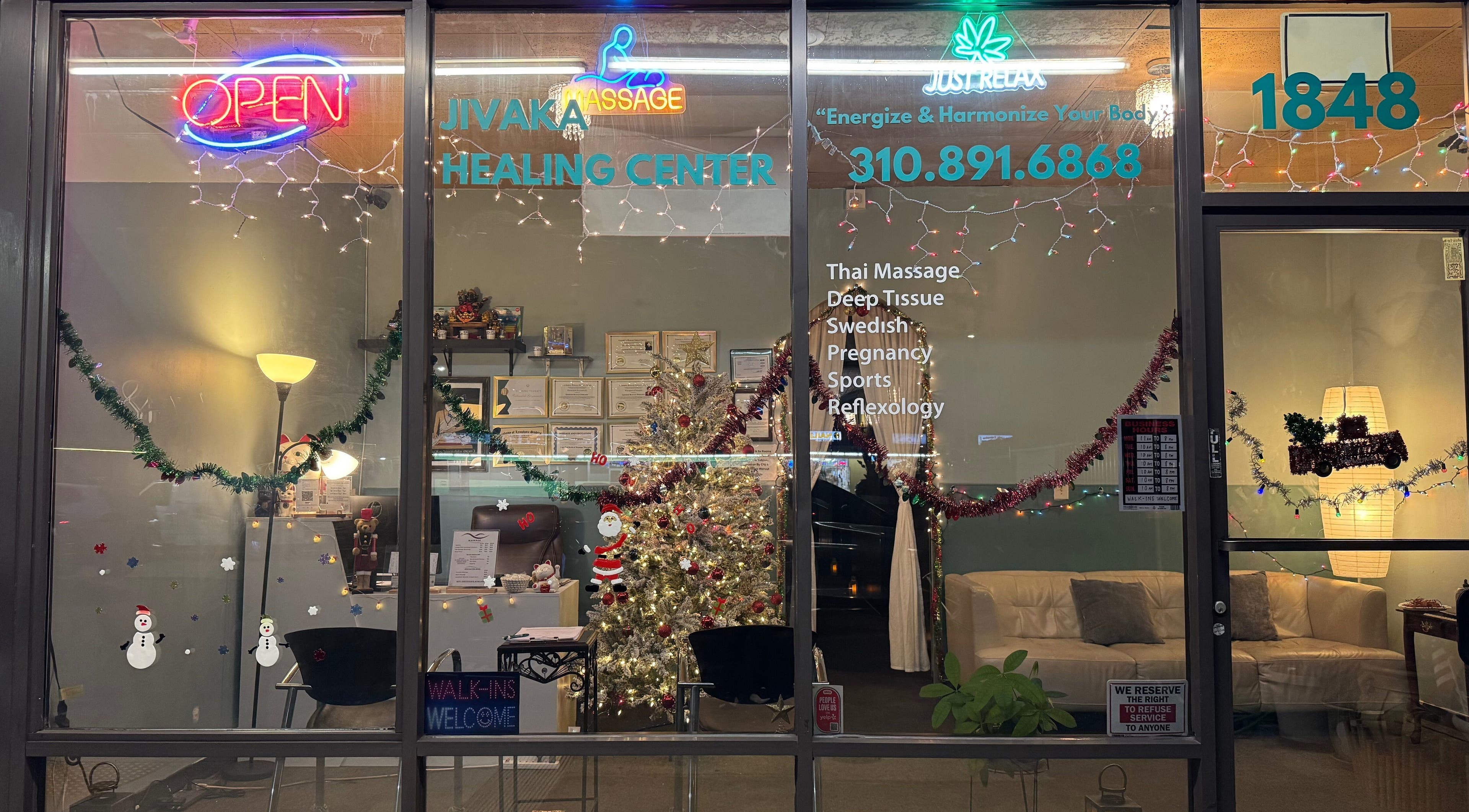 Festive front window of Jivaka Massage & Wellness, Lomita, California, US, with holiday lights and decor.
