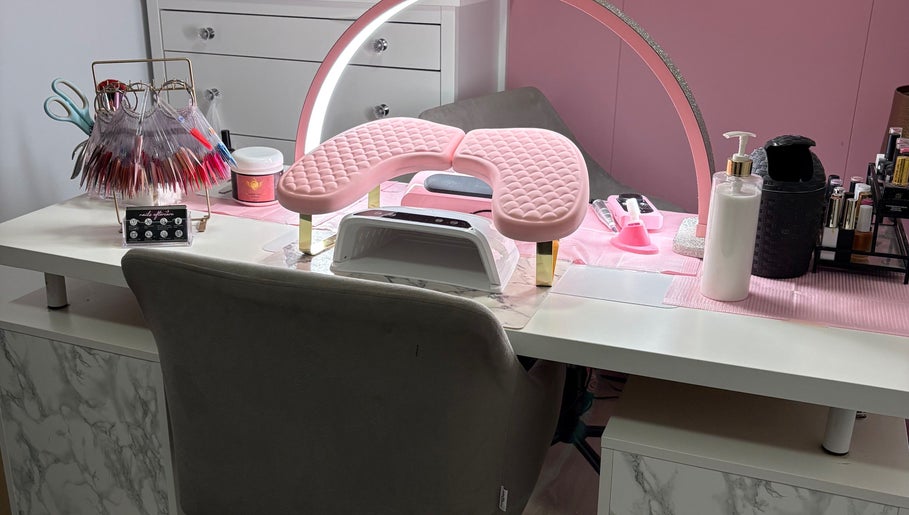 Een stijlvolle manicuretafel bij MD beauty, Nieuw-vennep, Noord-holland, NL, met roze kussen en nagellak displays.