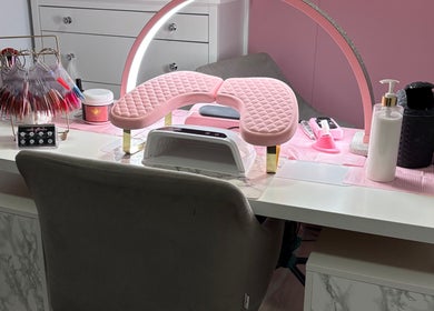 Een stijlvolle manicuretafel bij MD beauty, Nieuw-vennep, Noord-holland, NL, met roze kussen en nagellak displays.