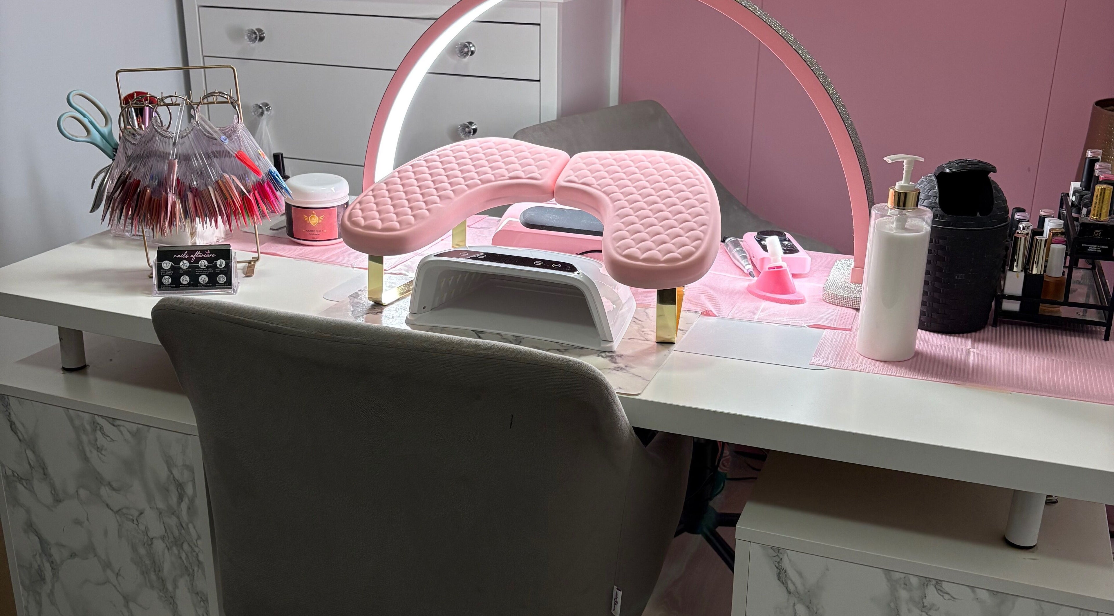 Een stijlvolle manicuretafel bij MD beauty, Nieuw-vennep, Noord-holland, NL, met roze kussen en nagellak displays.