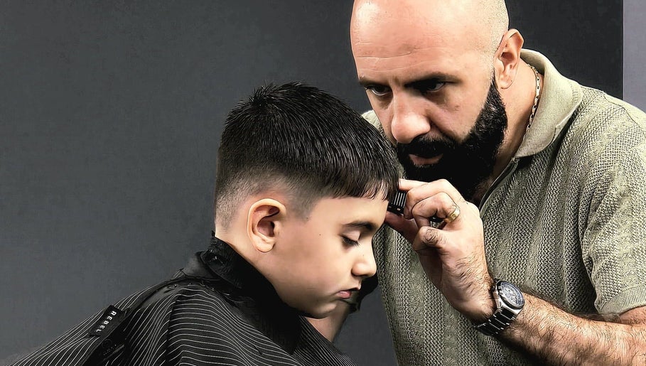 Barber at Barber Manch LA in Glendale, California, US, giving a precise haircut to young client.