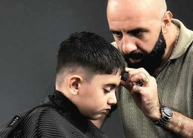 Barber at Barber Manch LA in Glendale, California, US, giving a precise haircut to young client.