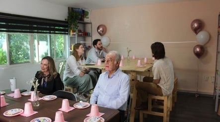 Ambiente relajado en VIDARTE LAE, Guadalajara, Jalisco, MX con decoración rosa y asistentes conversando.