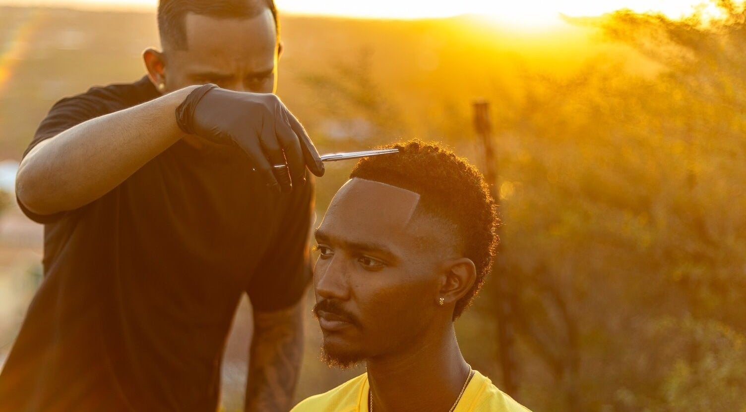 Valentino Barbershop barber giving a precise haircut at sunset in Willemstad, Curaçao, CW.