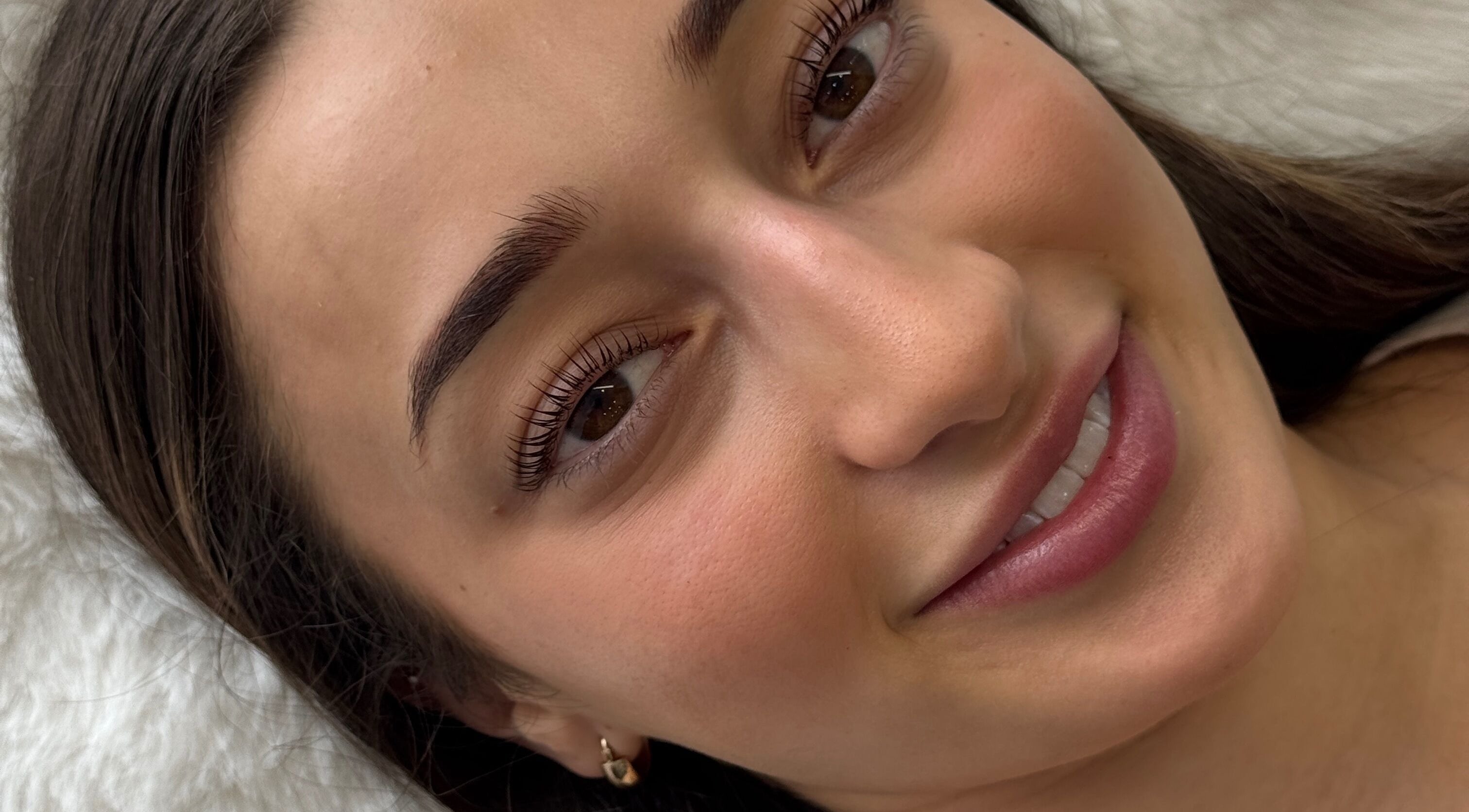 Woman with radiant skin smiling after treatment at Enhance By Alissa, Melbourne, Victoria, AU.