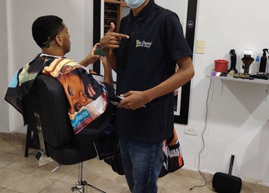 Barbero atendiendo cliente en LOS SANTOS BARBER SHOP, con diseño moderno. Cali, Valle Del Cauca, CO.