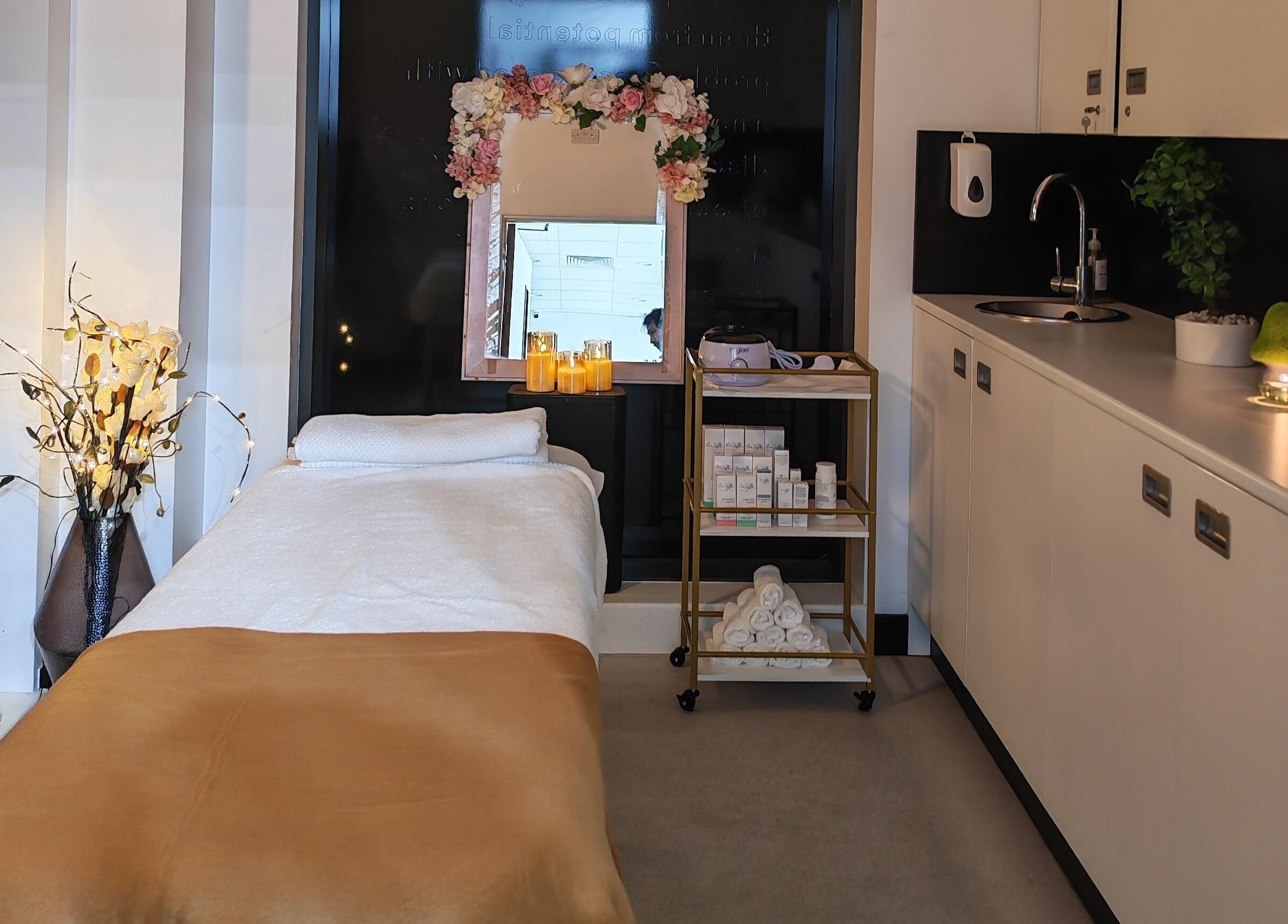 Cozy treatment room at Aura Hair N Beauty, London, England, GB with massage bed and decorative candles.