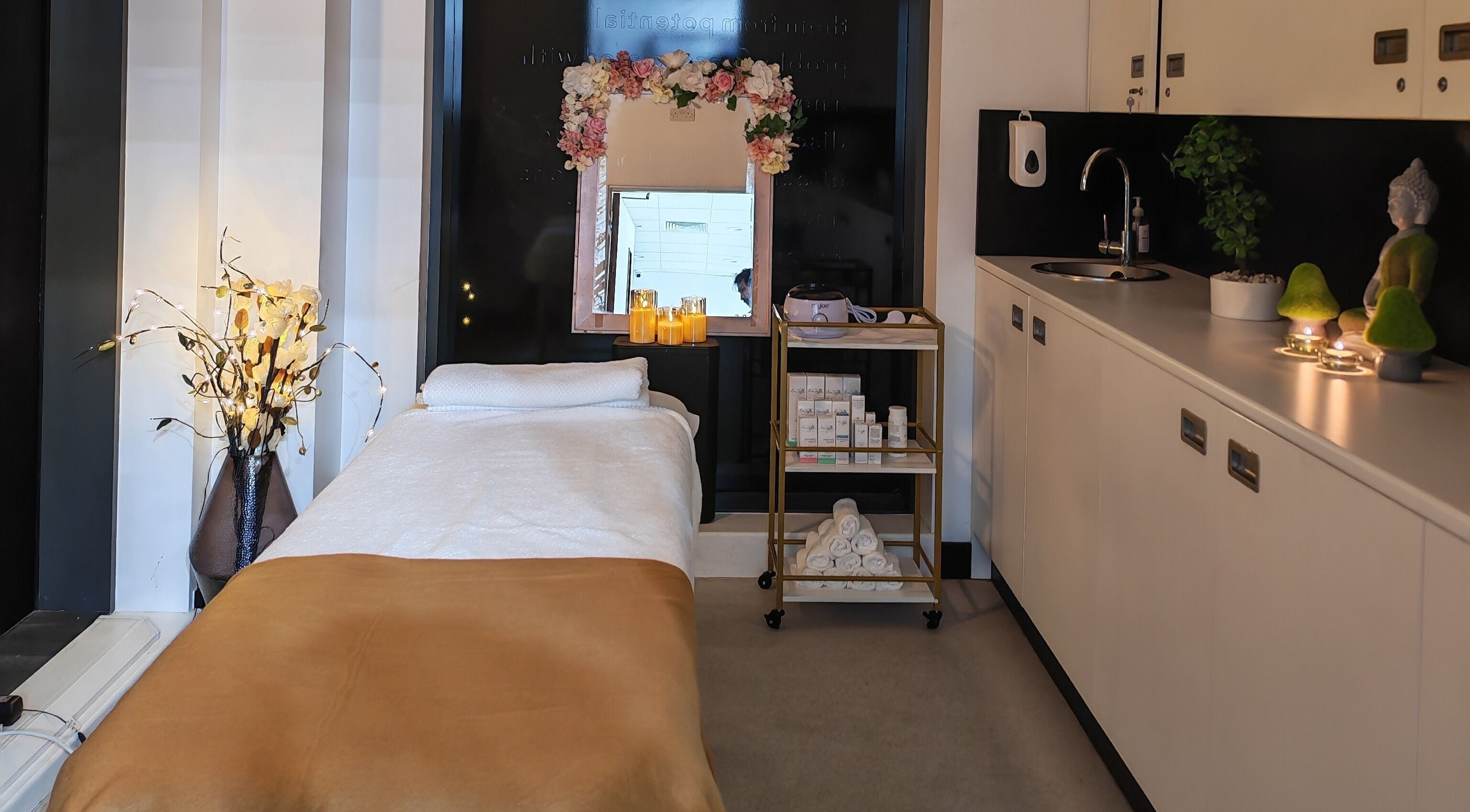 Cozy treatment room at Aura Hair N Beauty, London, England, GB with massage bed and decorative candles.