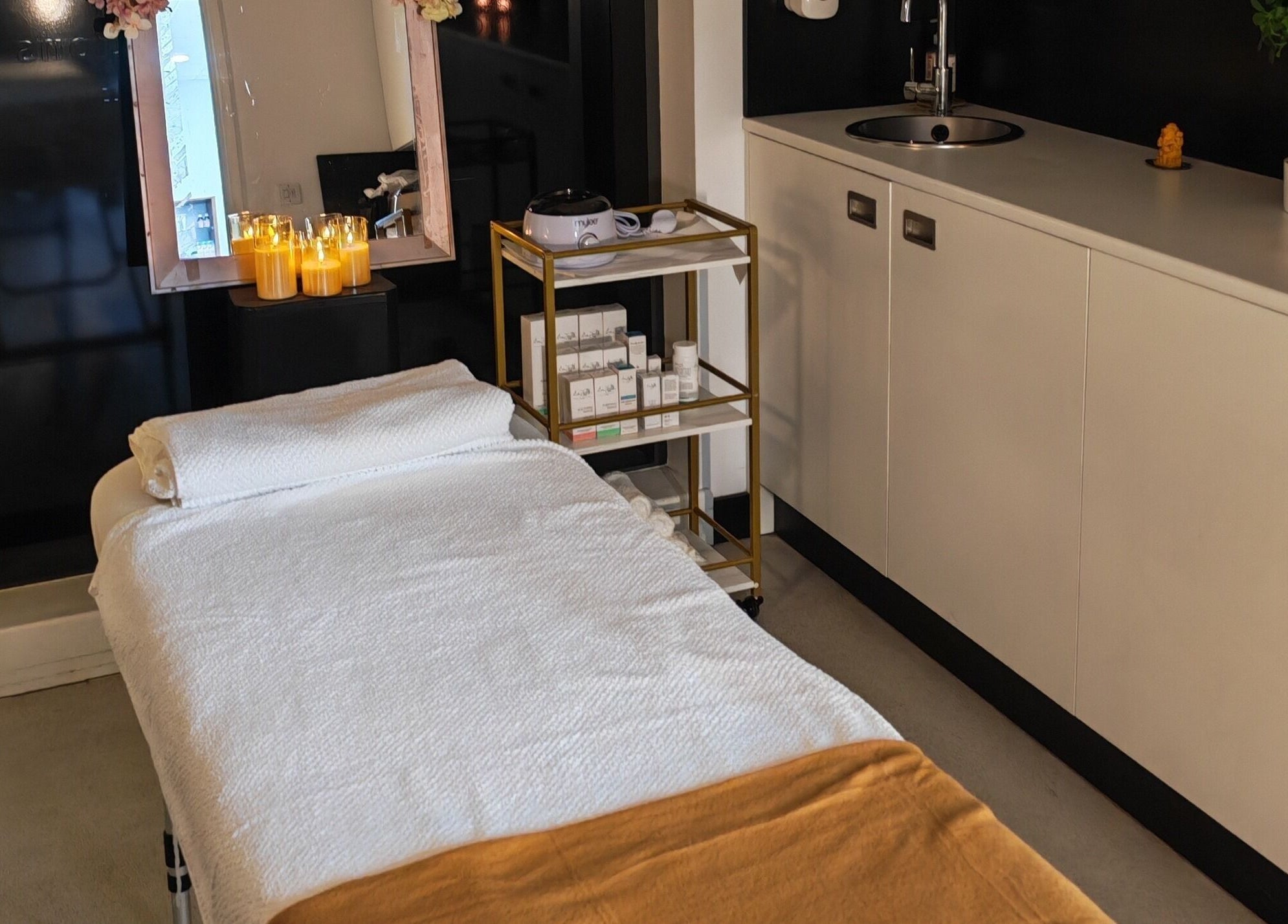 Relaxing spa room at Aura Hair N Beauty, London, England, GB with massage table, candles, and skincare products.
