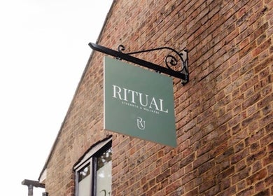 Deli White Massage RITUAL sign on brick wall in Berkhamsted, England, GB, highlighting wellness venue.