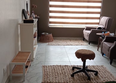 Relaxing seating area at Queen R Spa, Johannesburg, Gauteng, ZA with comfy chairs and soft lighting.