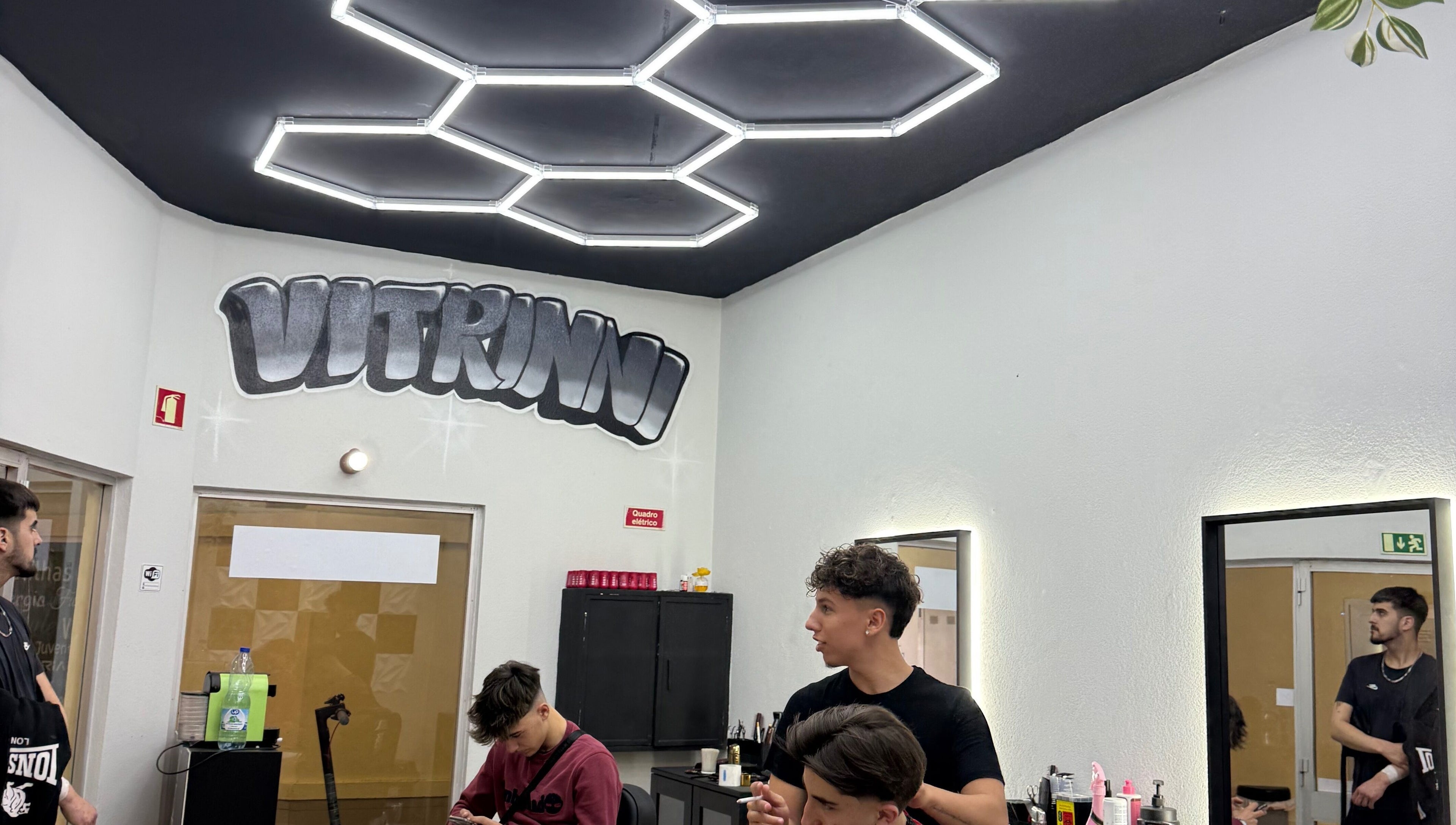 Interior moderno do salão Vitrinni em Gondomar, Porto, PT com teto geométrico e clientes desfrutando de serviços.