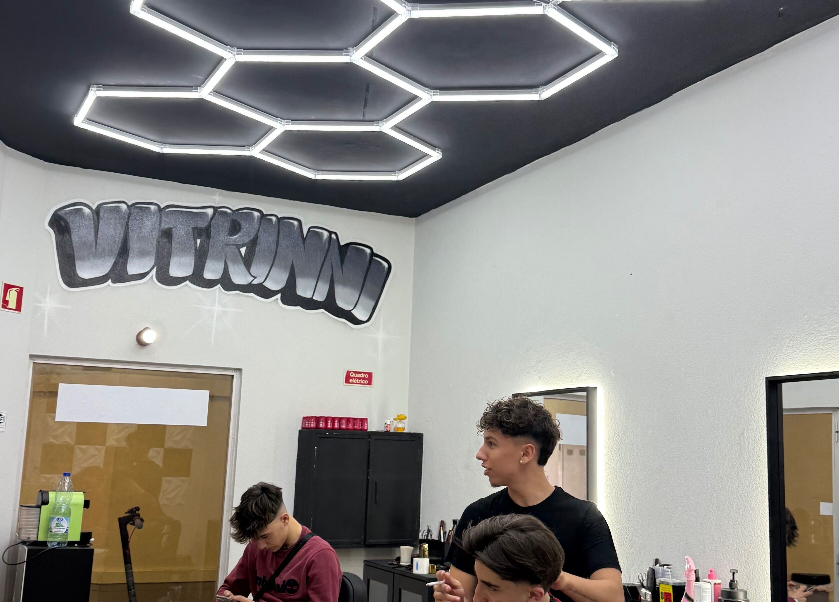 Interior moderno do salão Vitrinni em Gondomar, Porto, PT com teto geométrico e clientes desfrutando de serviços.