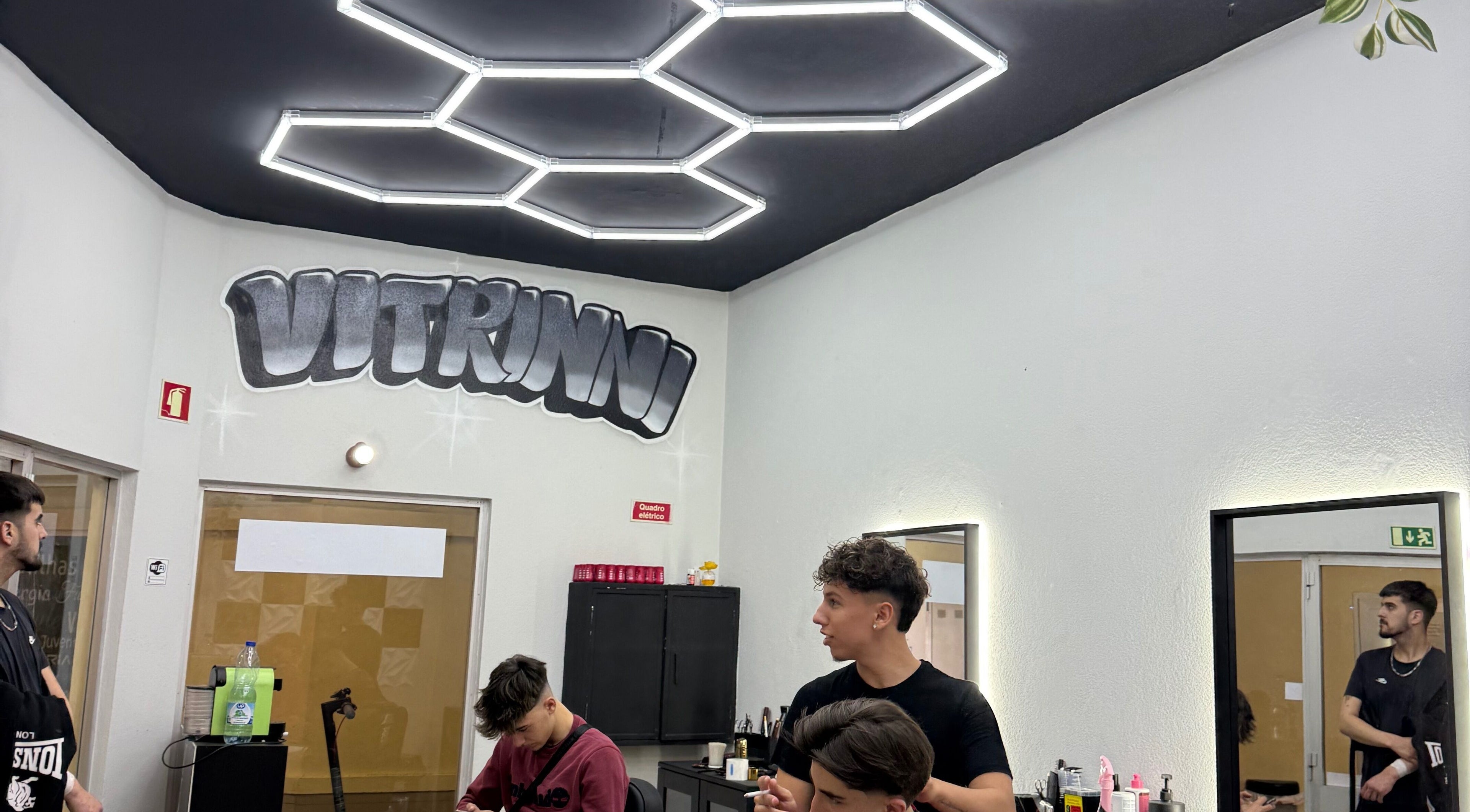 Interior moderno do salão Vitrinni em Gondomar, Porto, PT com teto geométrico e clientes desfrutando de serviços.