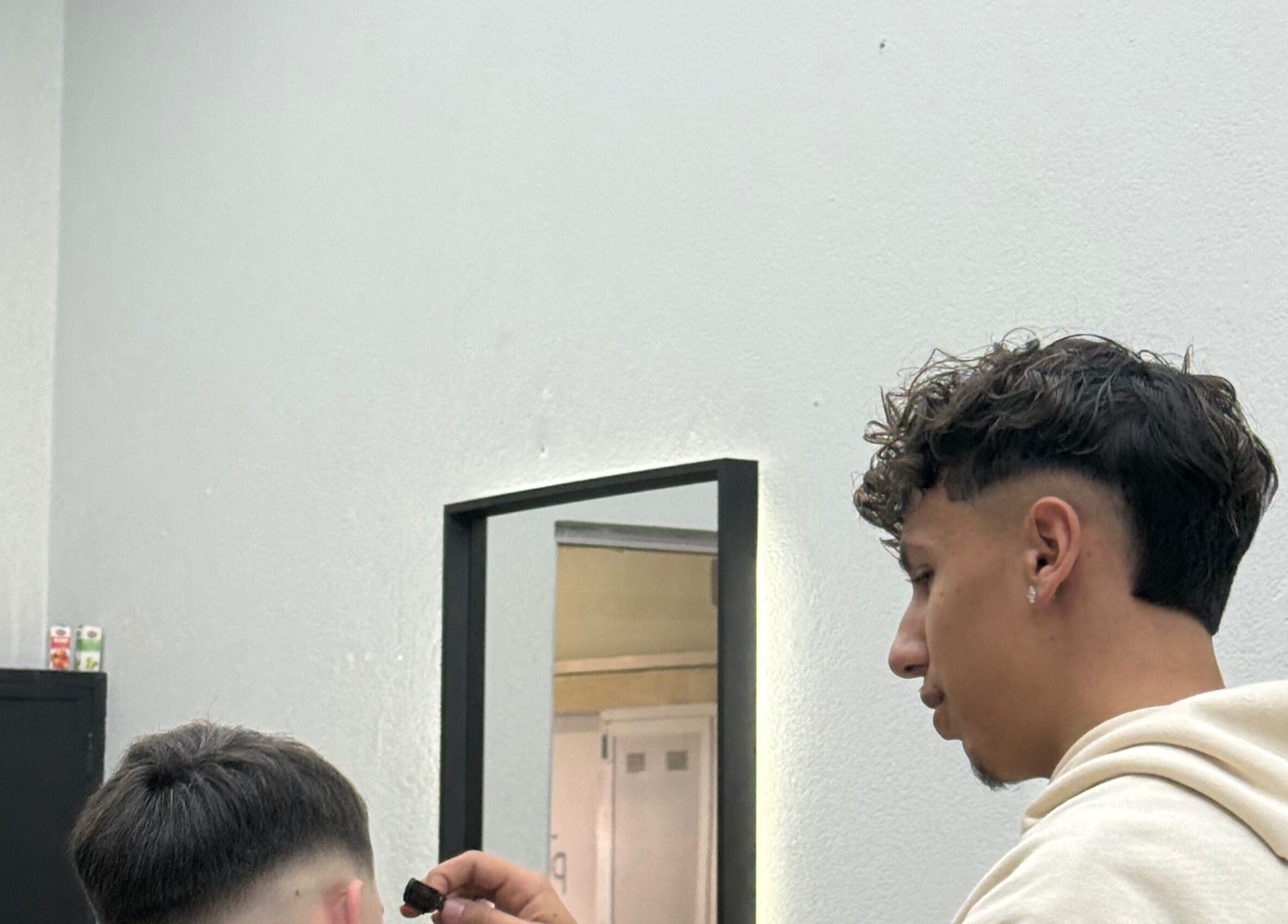 Barbeiro em Vitrinni, Gondomar, Porto, PT, ajusta cabelo de cliente com precisão.