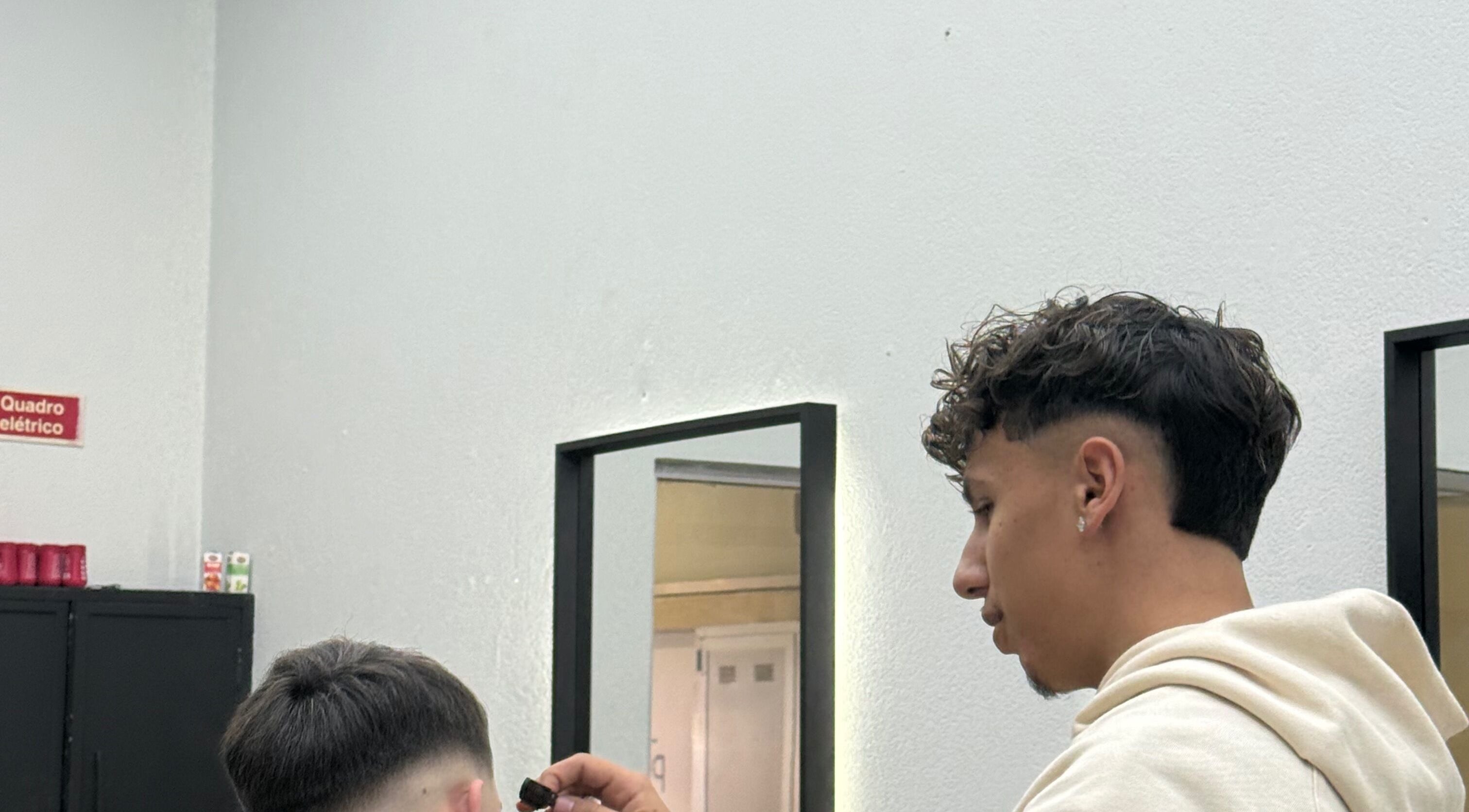 Barbeiro em Vitrinni, Gondomar, Porto, PT, ajusta cabelo de cliente com precisão.