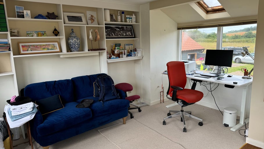 Cozy workspace at Signal Box Reflexology, Holt, England with blue sofa and modern desk overlooking countryside.
