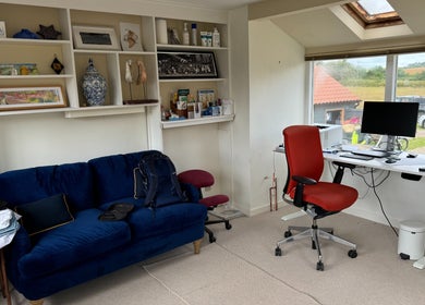Cozy workspace at Signal Box Reflexology, Holt, England with blue sofa and modern desk overlooking countryside.