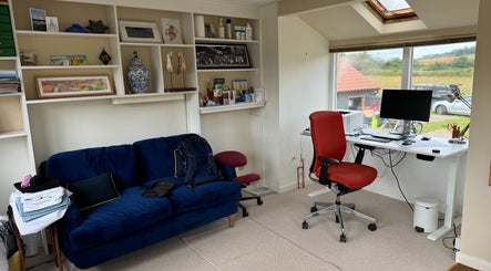 Cozy workspace at Signal Box Reflexology, Holt, England with blue sofa and modern desk overlooking countryside.