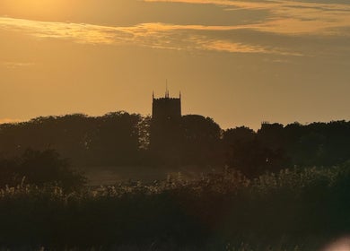 Dramatic sunset over Signal Box Reflexology in Holt, England, GB, highlighting a silhouette of a tower.