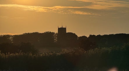 Dramatic sunset over Signal Box Reflexology in Holt, England, GB, highlighting a silhouette of a tower.