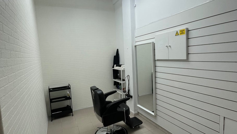 Interior moderno da Sam barbershop em Peniche, Leiria, PT, com cadeira preta e espelho grande.