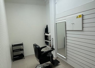 Interior moderno da Sam barbershop em Peniche, Leiria, PT, com cadeira preta e espelho grande.