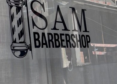 Logo da Sam Barbershop em Peniche, Leiria, PT refletido na vitrine.