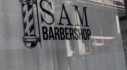 Logo da Sam Barbershop em Peniche, Leiria, PT refletido na vitrine.