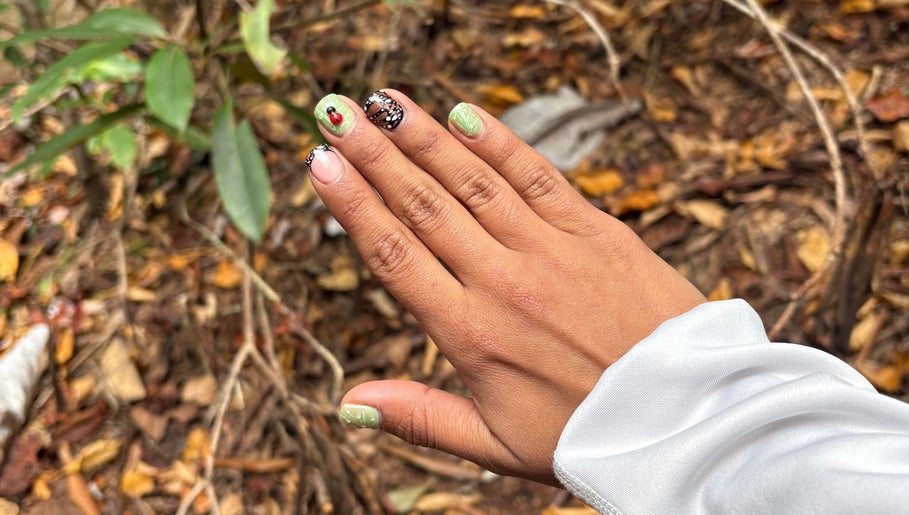 Nature-inspired nail art at Artistry Nail Lounge, Louisville, Kentucky, US features green and black nails.