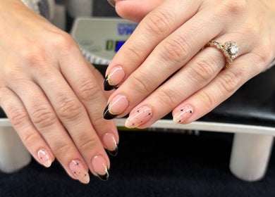 Elegant manicured hands with black and gold designs at Artistry Nail Lounge, Louisville, Kentucky, US.