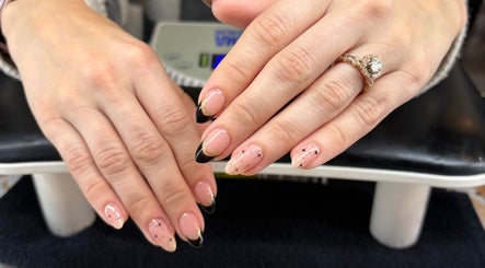 Elegant manicured hands with black and gold designs at Artistry Nail Lounge, Louisville, Kentucky, US.