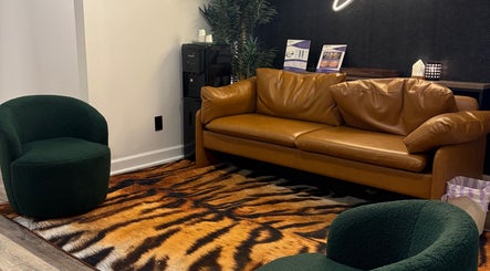 Chic seating area at Artistry Nail Lounge, Louisville, Kentucky, US with leather sofa and tiger-patterned rug.