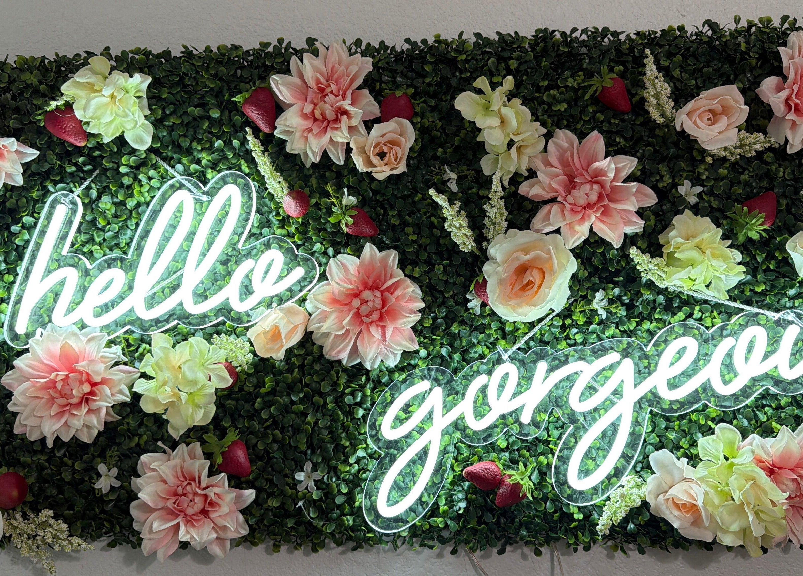 Neon 'hello gorgeous' sign on floral wall at Berry Smooth Waxing Co., Dickinson, Texas, US.