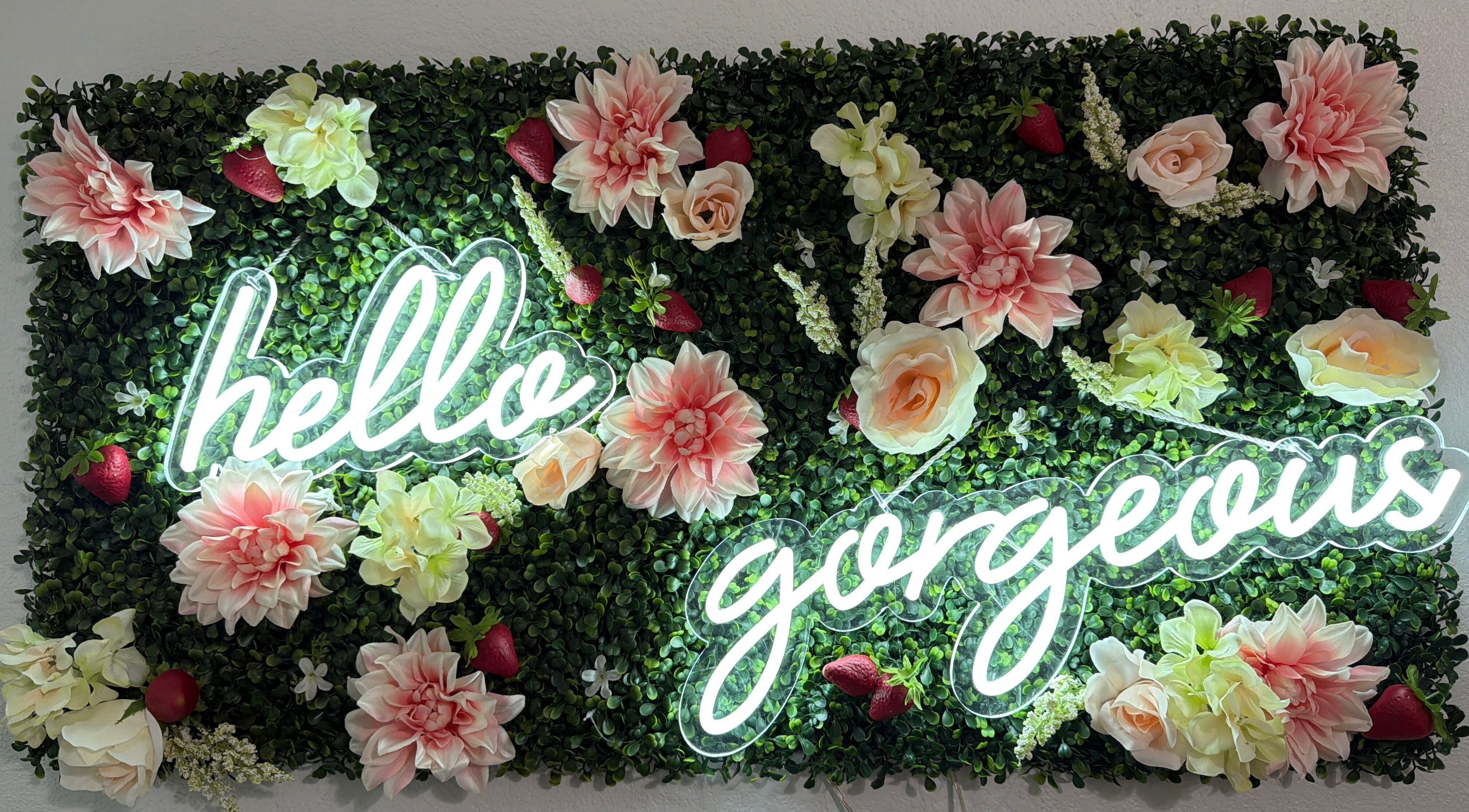 Neon 'hello gorgeous' sign on floral wall at Berry Smooth Waxing Co., Dickinson, Texas, US.