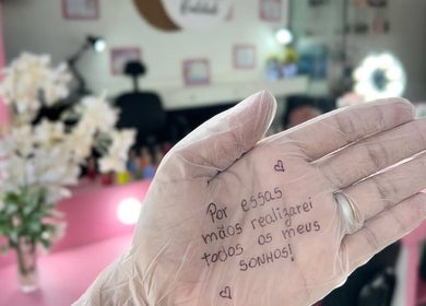 Mãos com luvas no Espaço Jeniffer Mota, Rio De Janeiro, com mensagem de inspiração na palma.