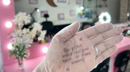 Mãos com luvas no Espaço Jeniffer Mota, Rio De Janeiro, com mensagem de inspiração na palma.